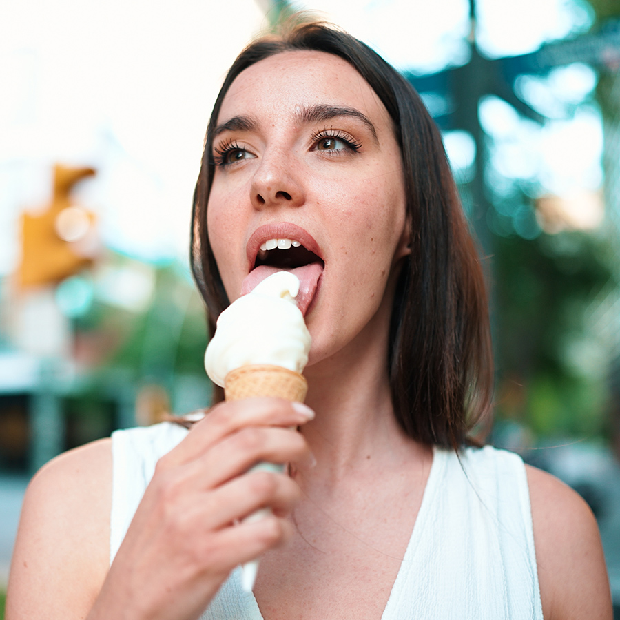 cute girl enjoys ice cream on modern city backgrou 85XQR7G